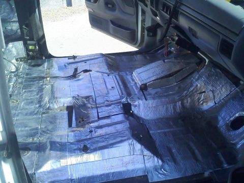 1994 Ford Bronco - The interior of a vehicle is shown with the floor stripped and covered in sound deadening material.