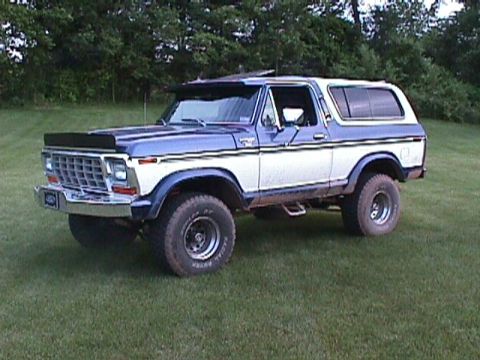 1978 Ford Bronco - This two-tone Ford Bronco is parked on a grassy lawn with trees in the background.
