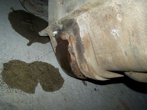 1989 Ford Bronco - Fuel tank shows significant rust and is leaking onto the garage floor.