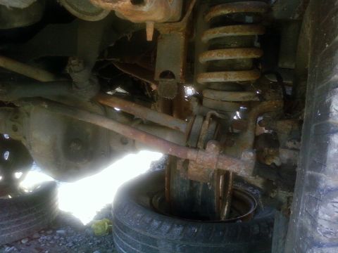 1989 Ford Bronco - Rusted suspension and axle components of a vehicle, possibly undergoing an axle swap.