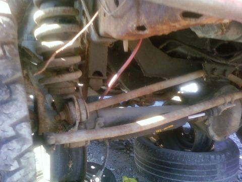 1989 Ford Bronco - Close-up of the rusty suspension and frame of an old vehicle, with a tire visible below.