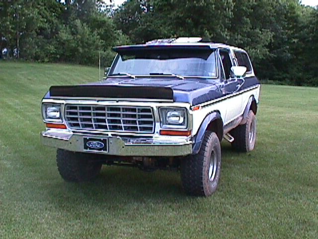 Lifted blue and white Ford Bronco parked front-on in a grassy yard