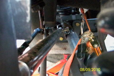 1989 Ford Bronco - The photo shows a close-up view of a vehicle's suspension system, with various metal components and an orange strap.