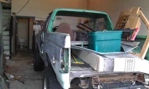 1995 Ford Bronco - This Ford Bronco, possibly undergoing restoration, is seen from the rear with its bed filled with various items including boxes and a green…