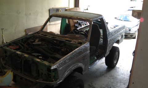 1995 Ford Bronco - This unfinished truck body is in a garage, undergoing restoration. Another vehicle is parked behind it.