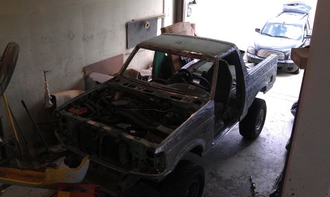 1995 Ford Bronco - This 1995 Ford Bronco is in a garage, likely for repairs or restoration, with another vehicle visible.
