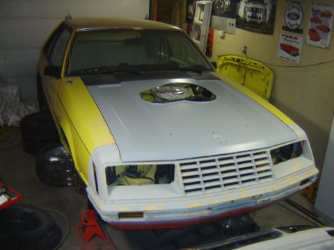 1979 Ford Mustang - This 1979 Ford Mustang is in a garage, possibly undergoing restoration, with its hood open to reveal the engine compartment.