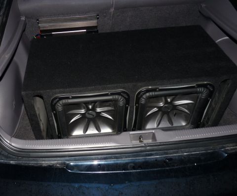 2006 Ford E350 - A view of dual subwoofers installed in the cargo area of a vehicle.