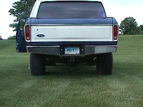 1978 Ford Bronco - Rear view of a 1978 Ford Bronco parked on grass with the driver's door ajar.