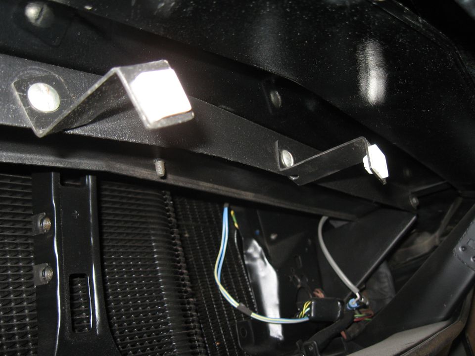 Close-up of car's radiator and black metal mounting brackets with wires