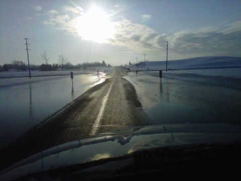 2011 Ford 427 - Winter scene shows a flooded road stretching into the distance with snow banks on either side.