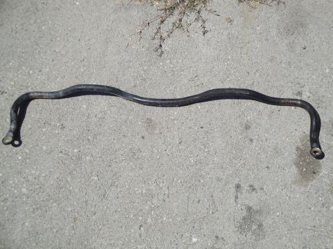 2003 Ford Taurus - A black sway bar lies on a concrete surface, likely a replacement part for a vehicle.