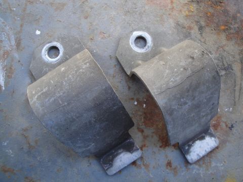 2003 Ford Taurus - Pair of sway bar brackets shown on a weathered metal background.