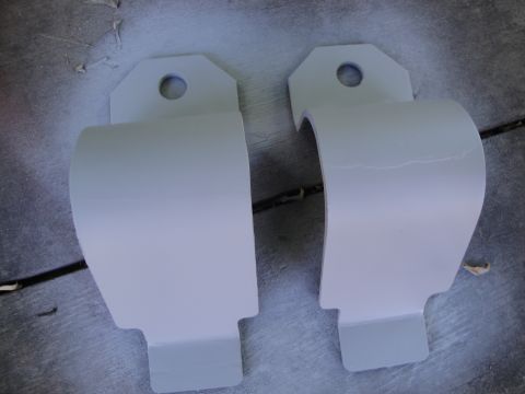 2003 Ford Taurus - Two painted metal brackets, possibly for a sway bar, are shown against a textured surface.