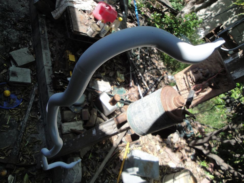 gray sway bar lying on the ground next to junk
