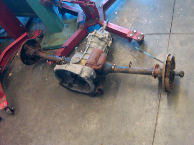 Transmission and rear axle assembly hanging from a red engine hoist