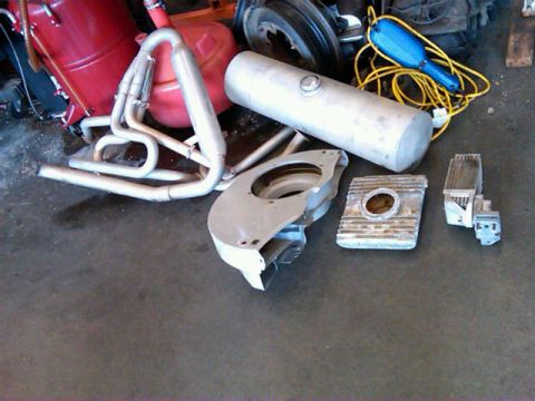 1995 Ford F-150 - Various automotive parts, including an exhaust system and engine components, are laid out on a concrete surface.