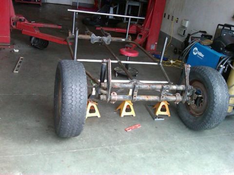 1995 Ford F-150 - A custom buggy frame is shown on jack stands in a garage, with a Miller welder in the background.