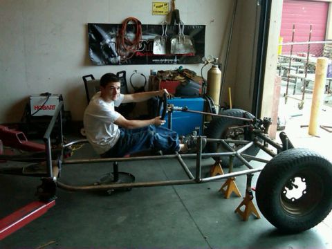 1995 Ford F-150 - A person sits in a custom-built tube frame chassis, which is supported by jack stands in a garage workshop.