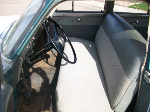 1952 Ford Mainline - The interior of this classic car features a two-tone bench seat and a large steering wheel.