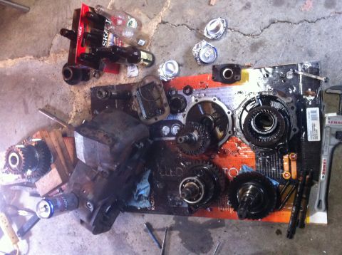 1989 Ford Bronco - Disassembled transfer case components and associated parts are spread out on a surface, with empty beverage containers visible.