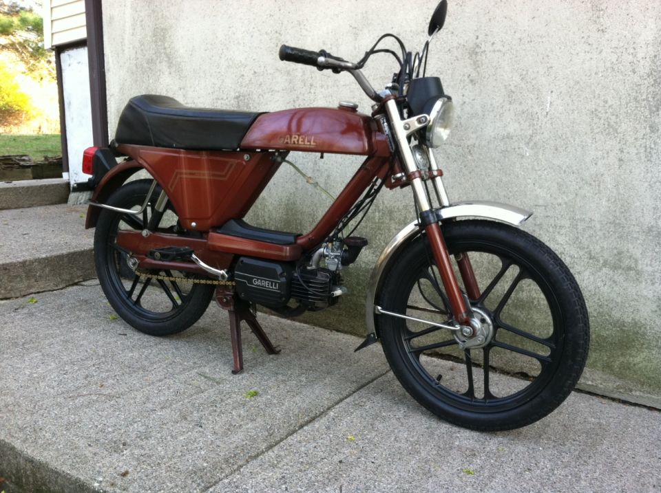 Garelli moped parked on concrete, side view. Text on engine casing reads GARELLI