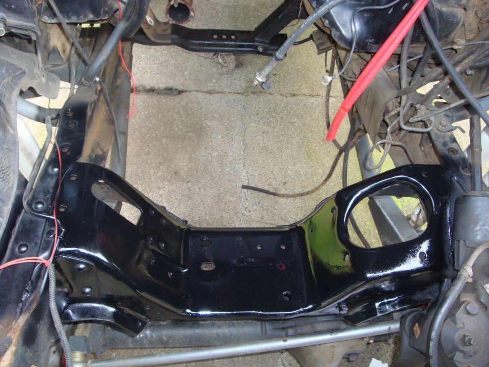 Freshly painted black front frame crossmember on a stripped truck chassis