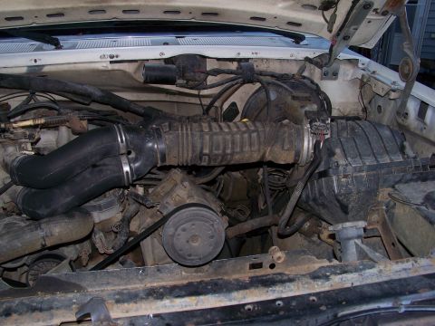 1989 Ford Bronco - Engine bay of a Ford truck shot from the front with the grille and radiator removed, showing the black plastic air box on the passenger sid…