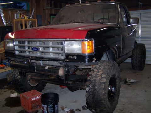 1988 Ford F-250 - This 1988 Ford F-250 truck is shown in a garage with a red hood and lifted suspension.