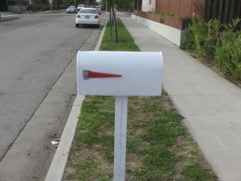 1968 Ford Mustang - A white mailbox stands by the curb on a residential street with a parked car in the background.