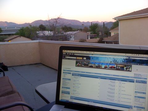 1968 Ford Mustang - A laptop is open on a patio table, displaying a car enthusiast website with a scenic mountain view at dusk.