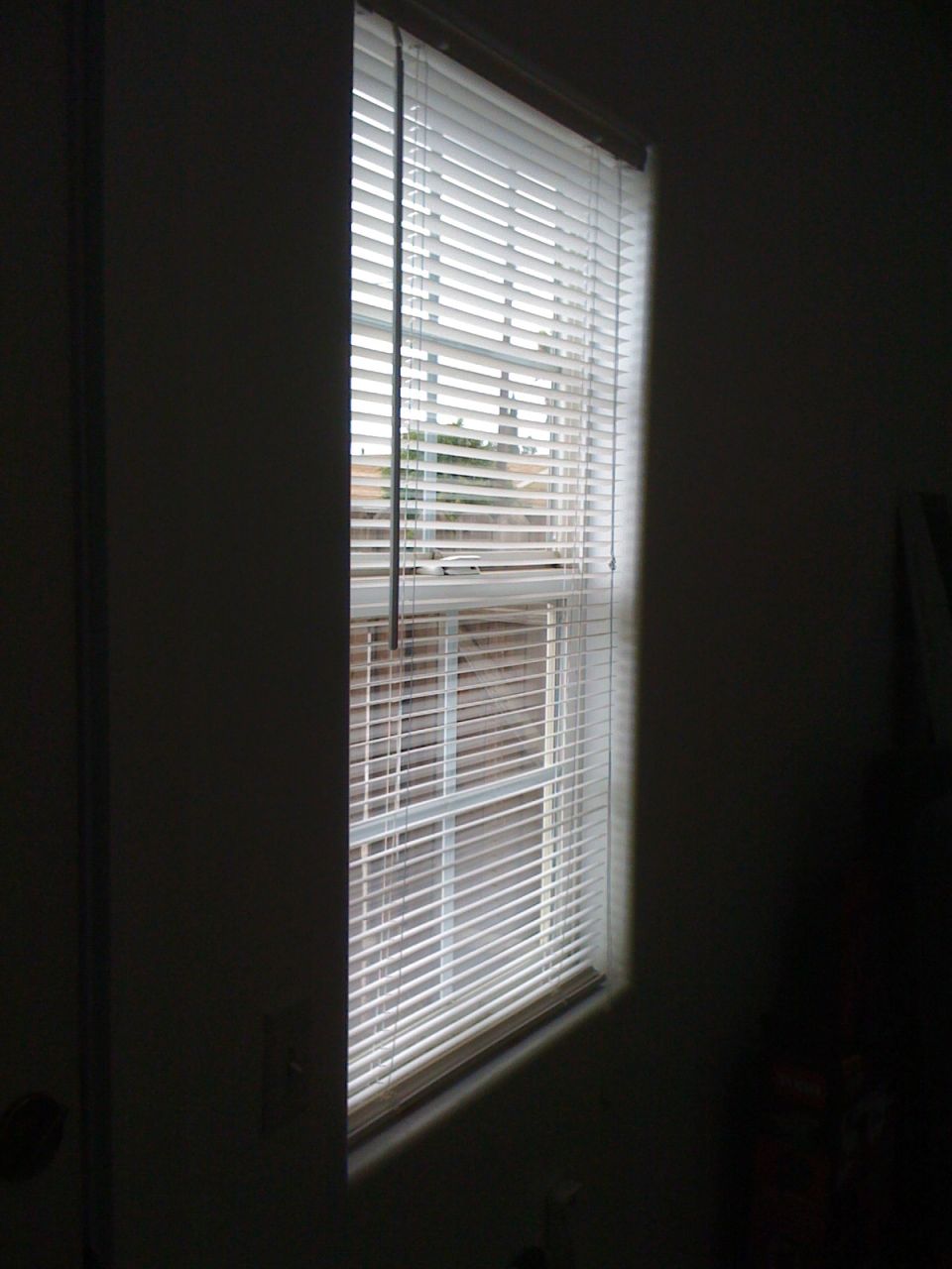 window with horizontal blinds letting light into a dark room