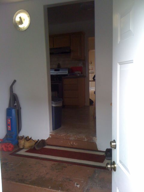 1968 Ford Mustang - View from an open doorway into a home, showing a hallway leading to a kitchen area with appliances and cabinets visible.