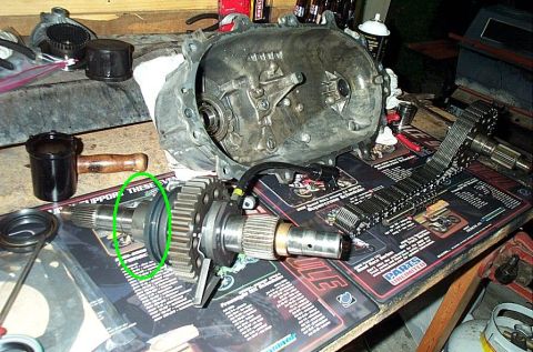 1995 Ford Bronco - A disassembled transfer case sits on a workbench atop a Parts Unlimited shop mat, with the main housing and an output shaft assembly laid o…