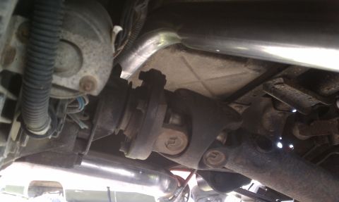 1996 Ford Bronco - Close-up of the vehicle's undercarriage, focusing on the driveshaft and exhaust system components.