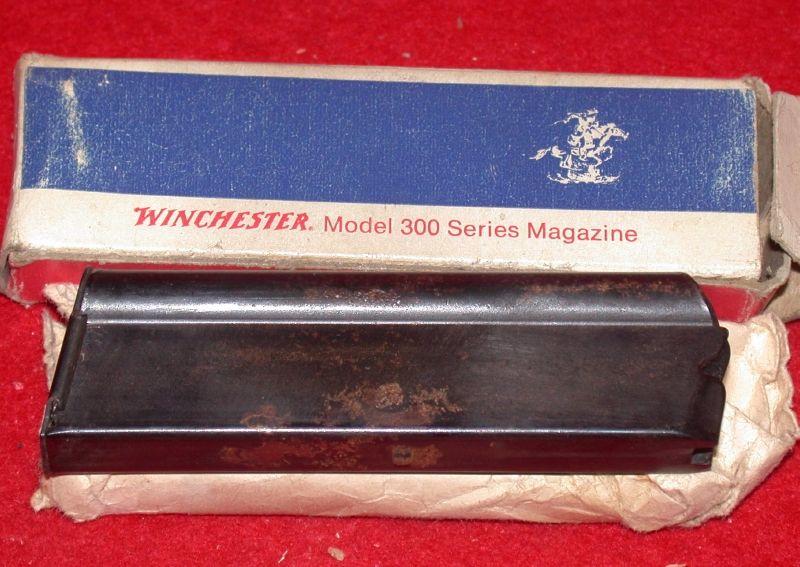 Rusty blued Winchester Model 300 series .22 rifle magazine beside its original blue box