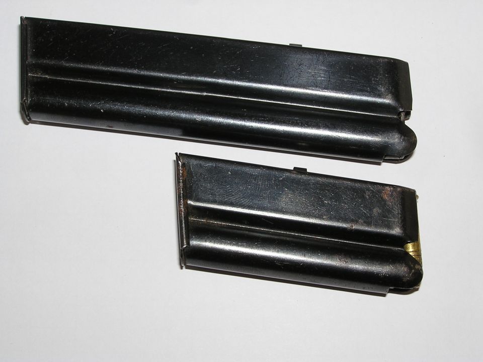 Long and short blued .22 rifle magazines lying at an angle on a white background
