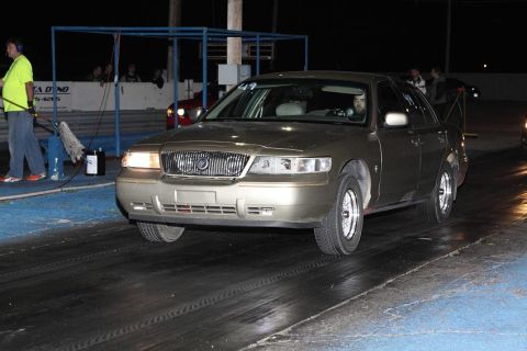 2000 Mercury Grand Marquis - A gold Mercury Grand Marquis is lined up on a drag strip at night, ready for a race.
