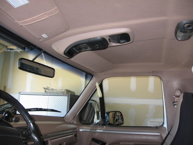 Tan headliner interior of a truck showing overhead console, rearview mirror, sun visor and side mirror