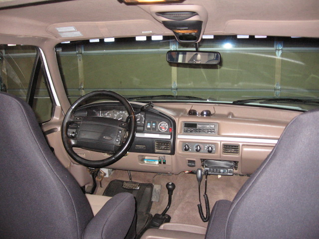 Tan interior of Ford truck with black steering wheel, dash controls and mounted CB radio handset