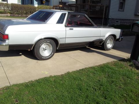 1970 Ford Ranchero - This 1977 Mercury Monarch coupe features a two-tone silver and black paint scheme with a black vinyl roof.