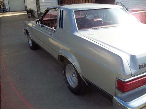 1970 Ford Ranchero - Silver coupe with a black vinyl roof and red interior parked on a concrete driveway.