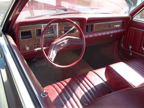 1970 Ford Ranchero - The interior of a 1977 Ford Granada features a red vinyl bench seat and wood-grain trim on the dashboard.