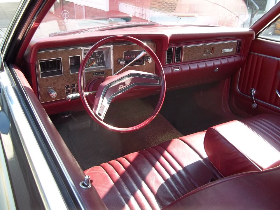 Red interior of a 1977 Ford Granada, showing the dashboard, steering wheel, and seats