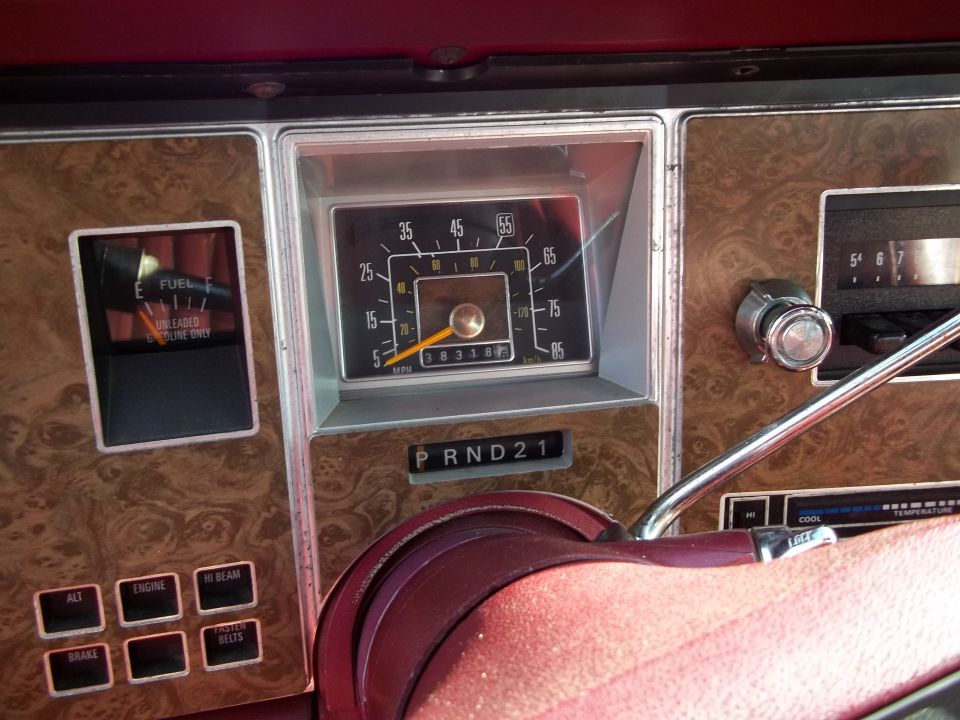 Car dashboard with faux wood grain, fuel gauge, speedometer, and PRND21 gear selector