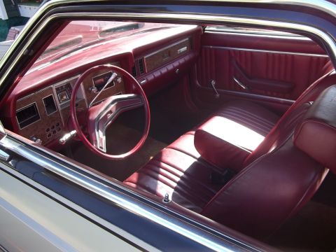 1970 Ford Ranchero - The interior of a car features red vinyl seats and a matching dashboard with woodgrain accents.