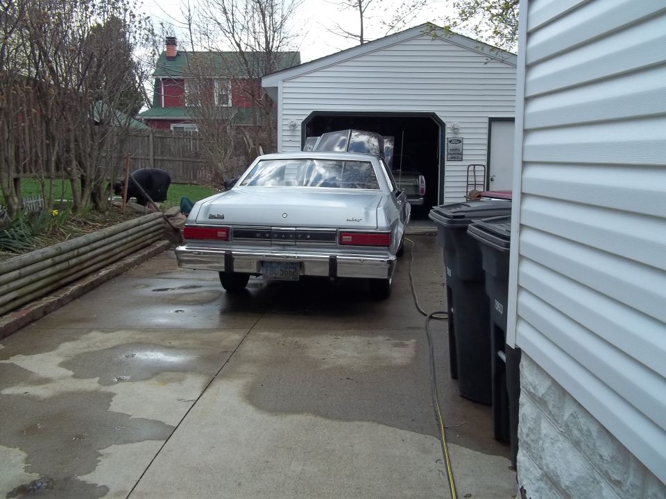 Silver sedan parked in driveway, another car in garage behind it