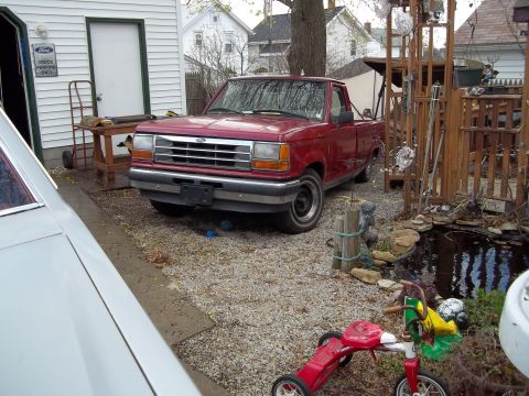 1970 Ford Ranchero - A red pickup truck is parked in a gravel driveway. The grille indicates it is likely a 1991 model.
