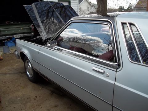 1970 Ford Ranchero - Silver sedan parked in a garage with its hood open, next to a green Ford pickup truck.