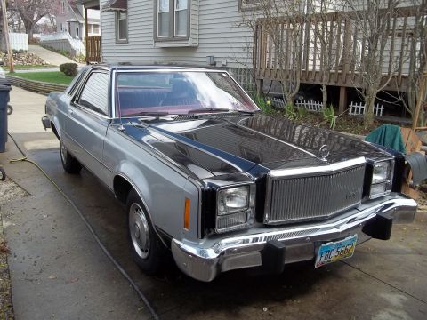1970 Ford Ranchero - This two-tone silver and black coupe utility, identified as a 1977 Mercury Cougar XR-7, is parked in a driveway.